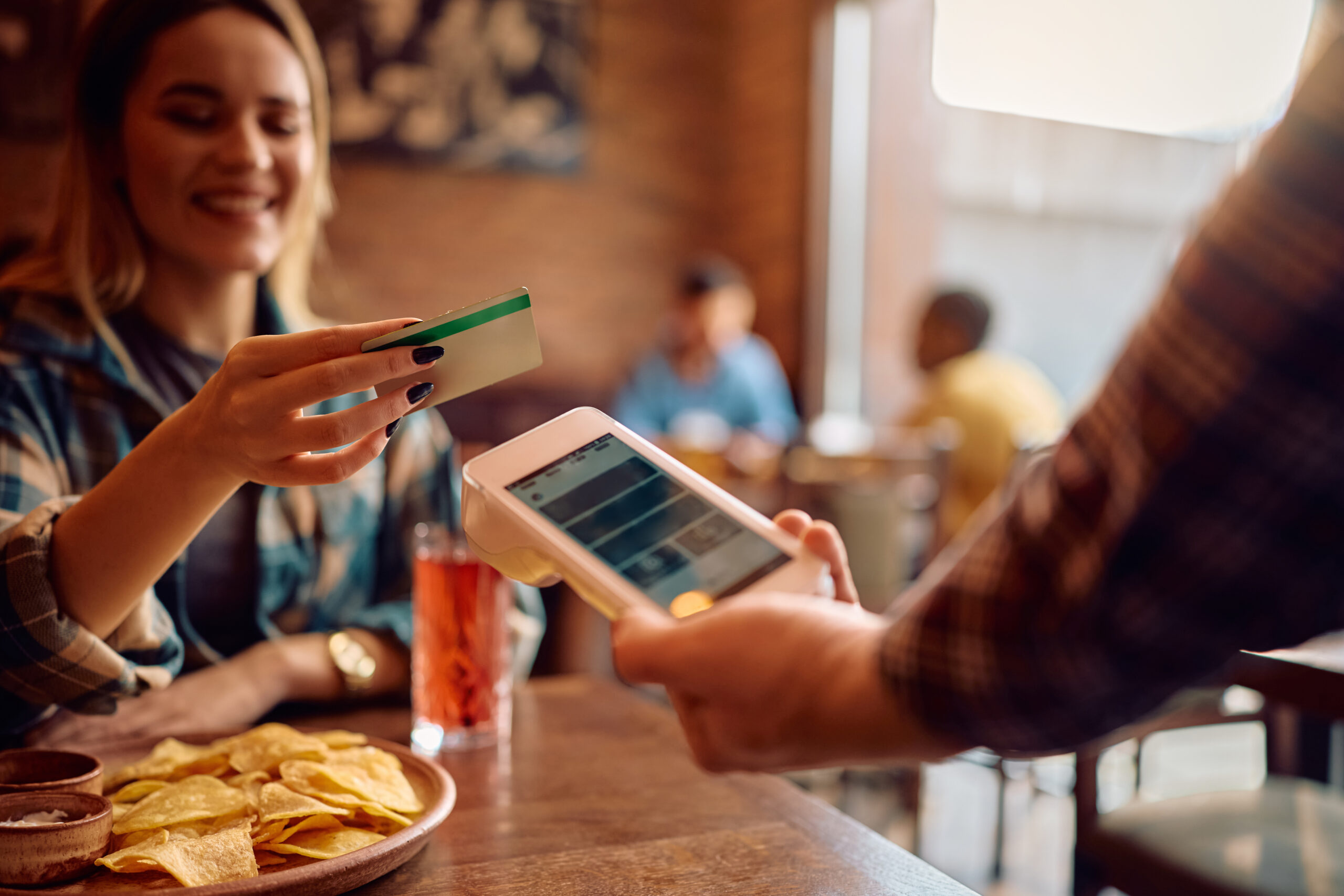 close up of woman paying contactless with credit card in a pub.